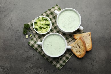 Photo of Tasty cucumber soup served on grey table, flat lay