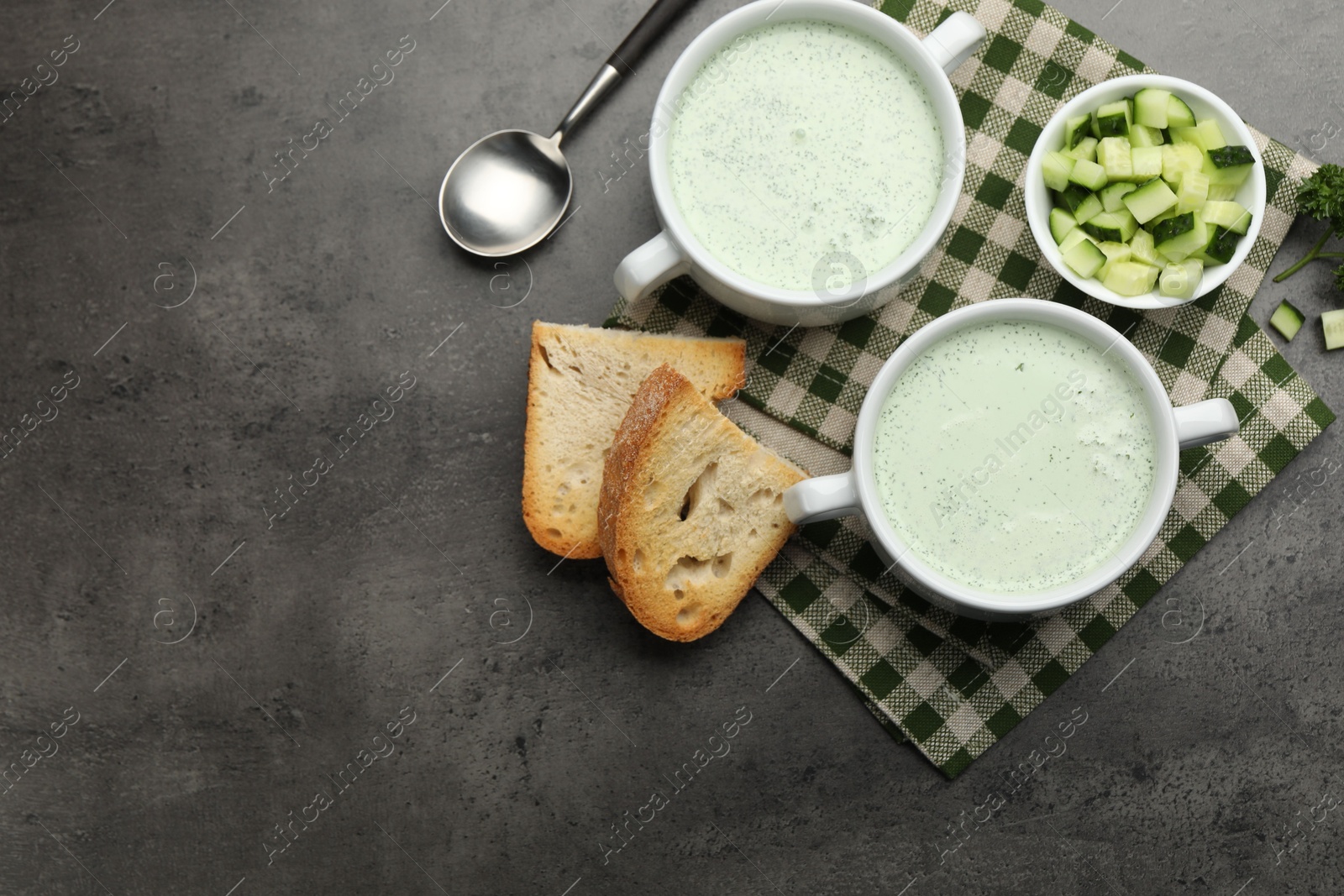Photo of Tasty cucumber soup served on grey table, flat lay. Space for text