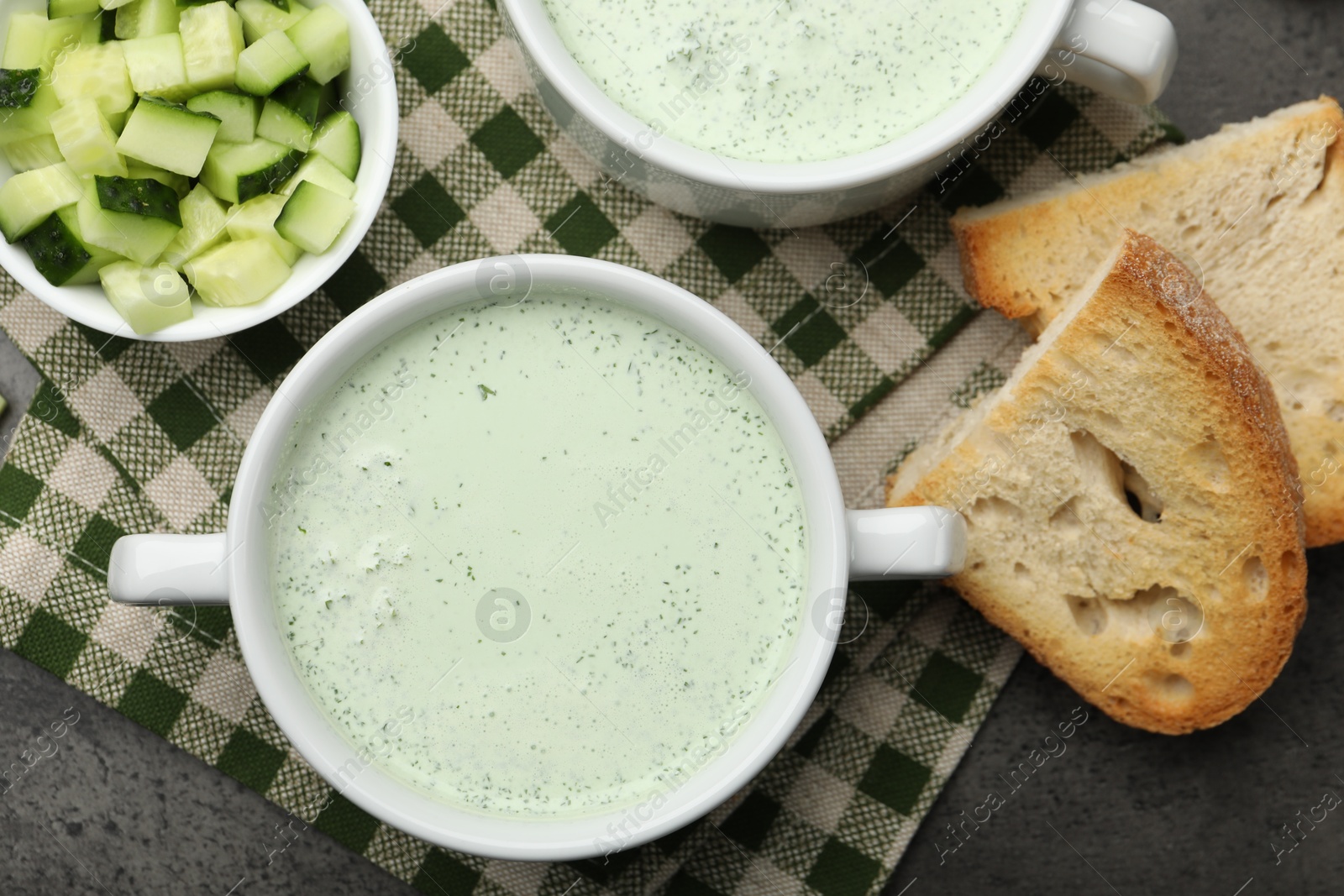 Photo of Tasty cucumber soup served on grey table, flat lay