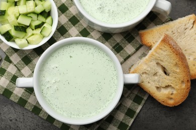 Photo of Tasty cucumber soup served on grey table, flat lay