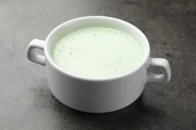 Photo of Tasty cucumber soup on grey table, closeup
