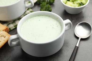 Photo of Tasty cucumber soup served on grey table, closeup