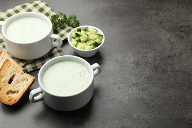 Photo of Tasty cucumber soup served on grey table. Space for text