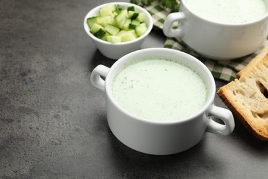 Photo of Tasty cucumber soup served on grey table, closeup. Space for text