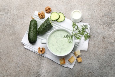 Photo of Tasty cucumber soup with dill, croutons, walnuts and vegetables on grey table, flat lay