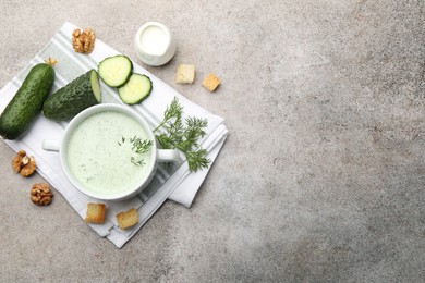 Photo of Tasty cucumber soup with dill, croutons, walnuts and vegetables on grey table, flat lay. Space for text