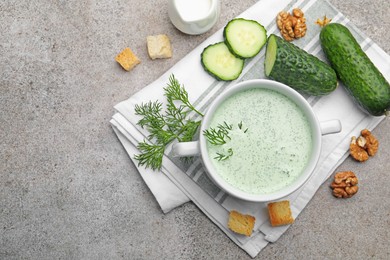 Photo of Tasty cucumber soup with dill, croutons, walnuts and vegetables on grey table, flat lay. Space for text