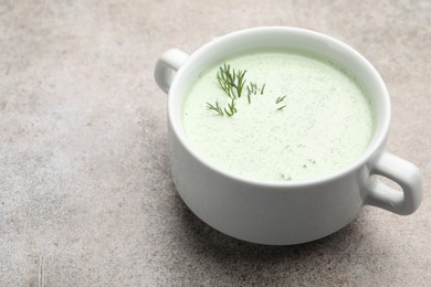 Photo of Tasty cucumber soup with dill on grey table, closeup. Space for text