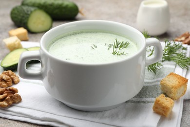 Photo of Tasty cucumber soup with dill, croutons, walnuts and vegetables on grey table, closeup