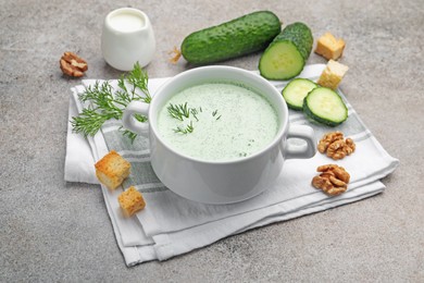 Photo of Tasty cucumber soup with dill, croutons, walnuts and vegetables on grey table