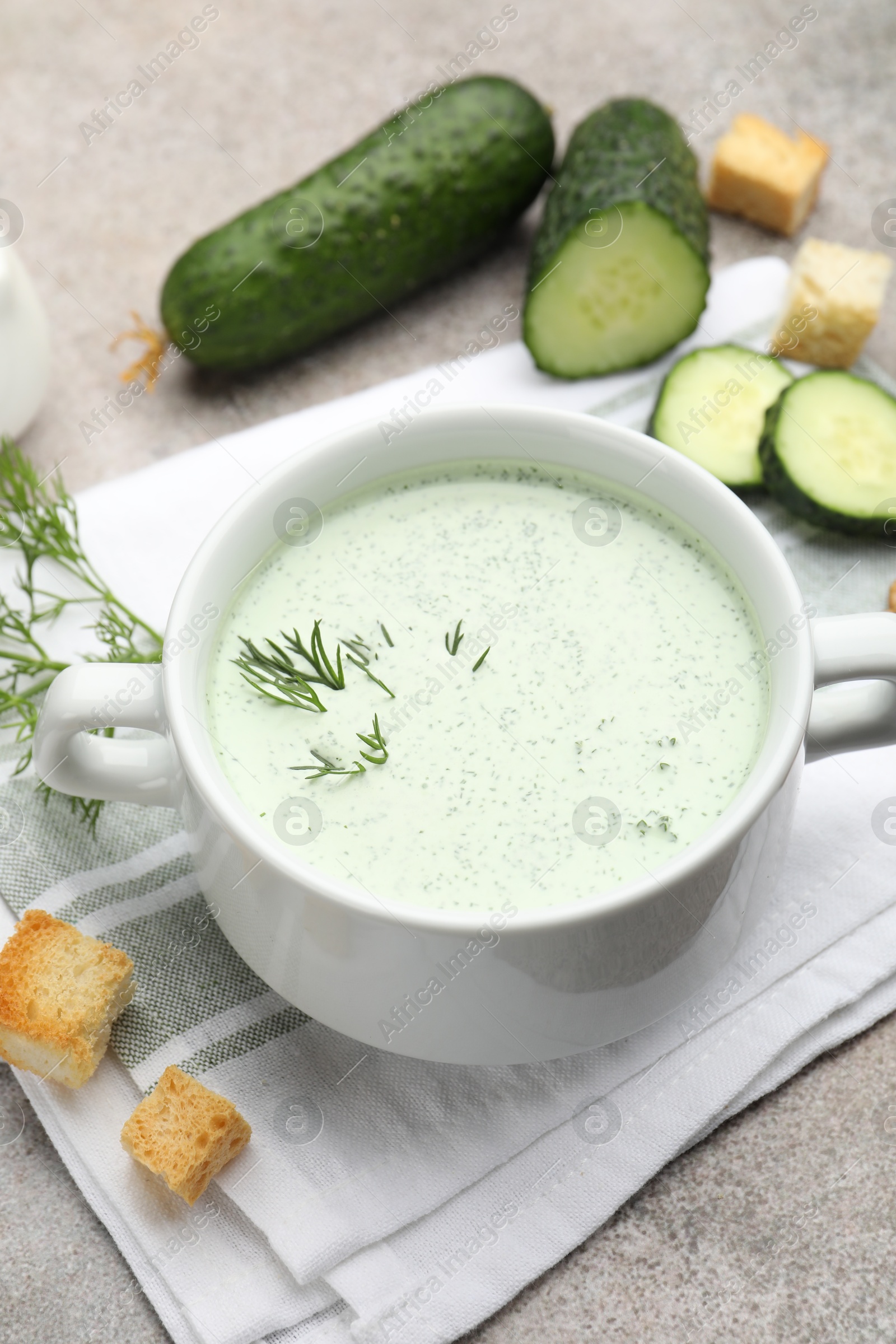 Photo of Tasty cucumber soup with dill, croutons, walnuts and vegetables on grey table