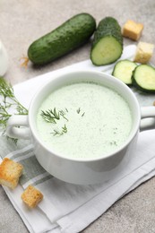 Photo of Tasty cucumber soup with dill, croutons, walnuts and vegetables on grey table