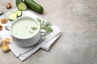Photo of Tasty cucumber soup with dill, croutons, walnuts and vegetables on grey table. Space for text