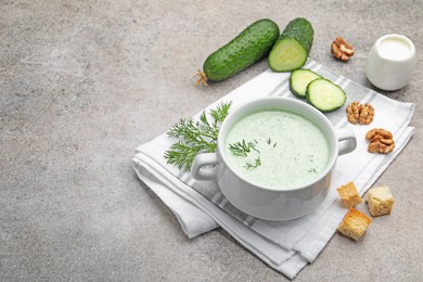 Photo of Tasty cucumber soup with dill, croutons, walnuts and vegetables on grey table. Space for text
