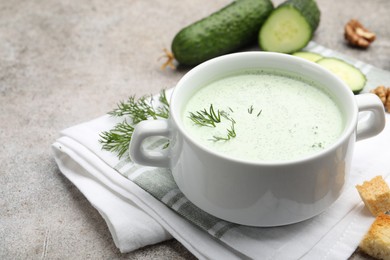Photo of Tasty cucumber soup with dill, croutons, walnuts and vegetables on grey table, closeup