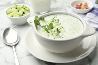 Photo of Tasty cucumber soup with dill and microgreens served on white marble table, closeup
