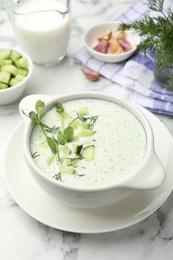 Photo of Tasty cucumber soup with dill, microgreens and ingredients on white marble table, closeup
