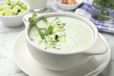 Photo of Tasty cucumber soup with dill, microgreens and ingredients on white marble table, closeup