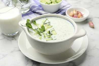 Photo of Tasty cucumber soup with dill, microgreens and ingredients on white marble table, closeup