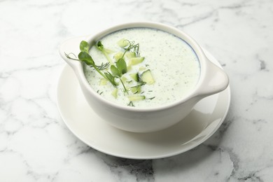 Photo of Tasty cucumber soup with dill and microgreens on white marble table, closeup
