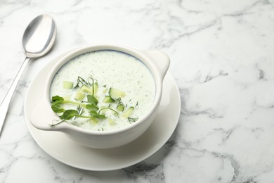 Photo of Tasty cucumber soup with dill and microgreens served on white marble table, closeup. Space for text