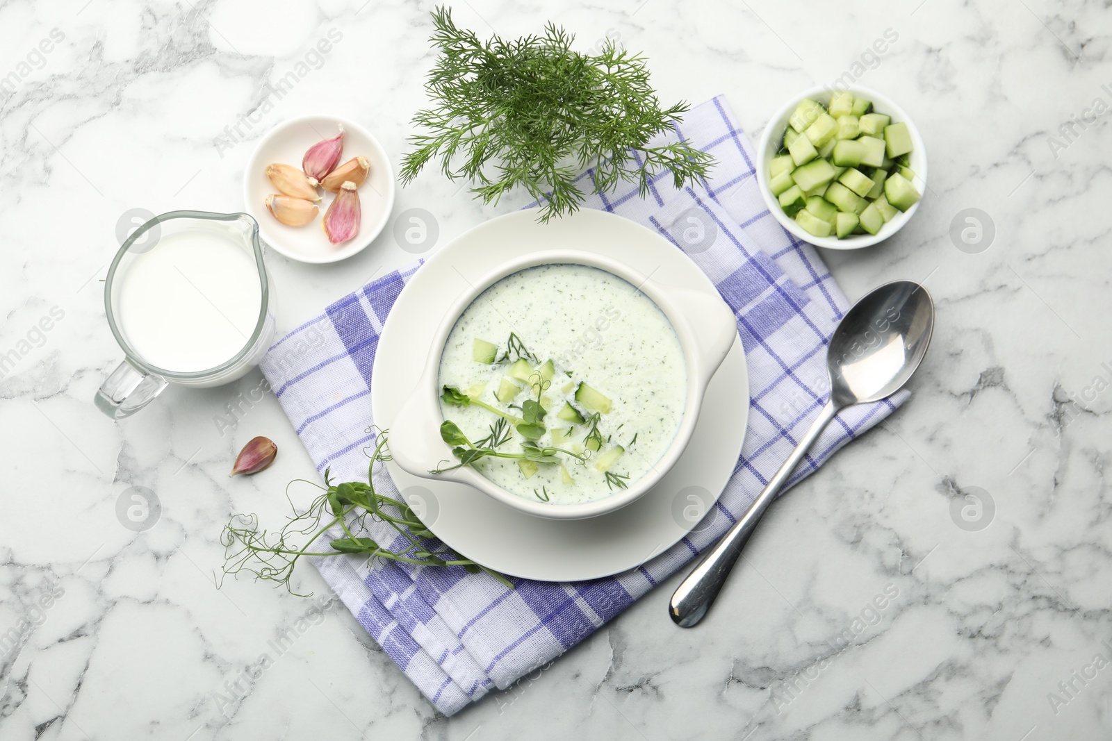 Photo of Tasty cucumber soup with dill and microgreens served on white marble table, flat lay