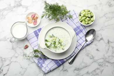 Photo of Tasty cucumber soup with dill and microgreens served on white marble table, flat lay