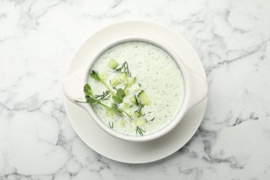 Photo of Tasty cucumber soup with dill and microgreens on white marble table, top view