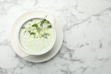 Photo of Tasty cucumber soup with dill and microgreens on white marble table, top view. Space for text