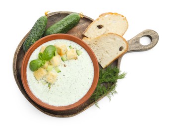 Photo of Tasty cucumber soup with croutons, basil, bread and ingredients isolated on white, top view