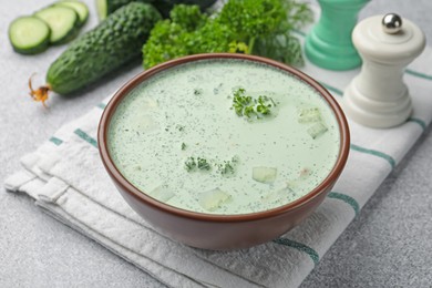 Photo of Tasty cucumber soup and ingredients on light grey table, closeup