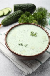 Photo of Tasty cucumber soup and ingredients on light grey table, closeup