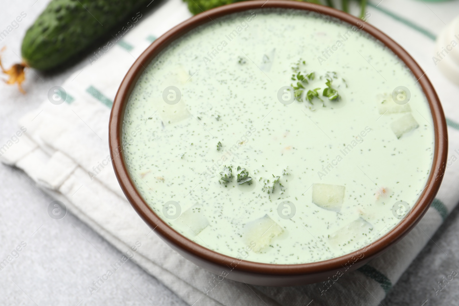Photo of Tasty cucumber soup and ingredients on light grey table, closeup
