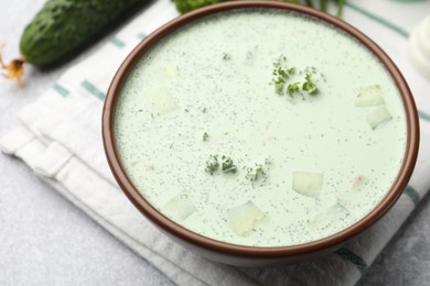 Photo of Tasty cucumber soup and ingredients on light grey table, closeup