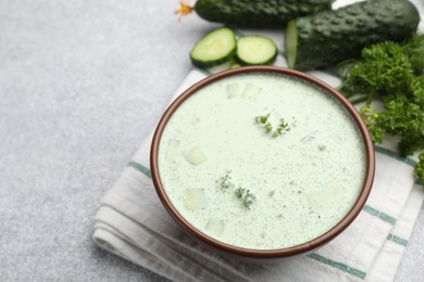Photo of Tasty cucumber soup and ingredients on light grey table, closeup