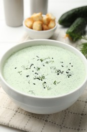 Photo of Tasty cucumber soup, croutons and ingredients on white wooden table, closeup