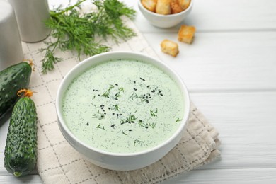 Photo of Tasty cucumber soup, croutons and ingredients on white wooden table, closeup