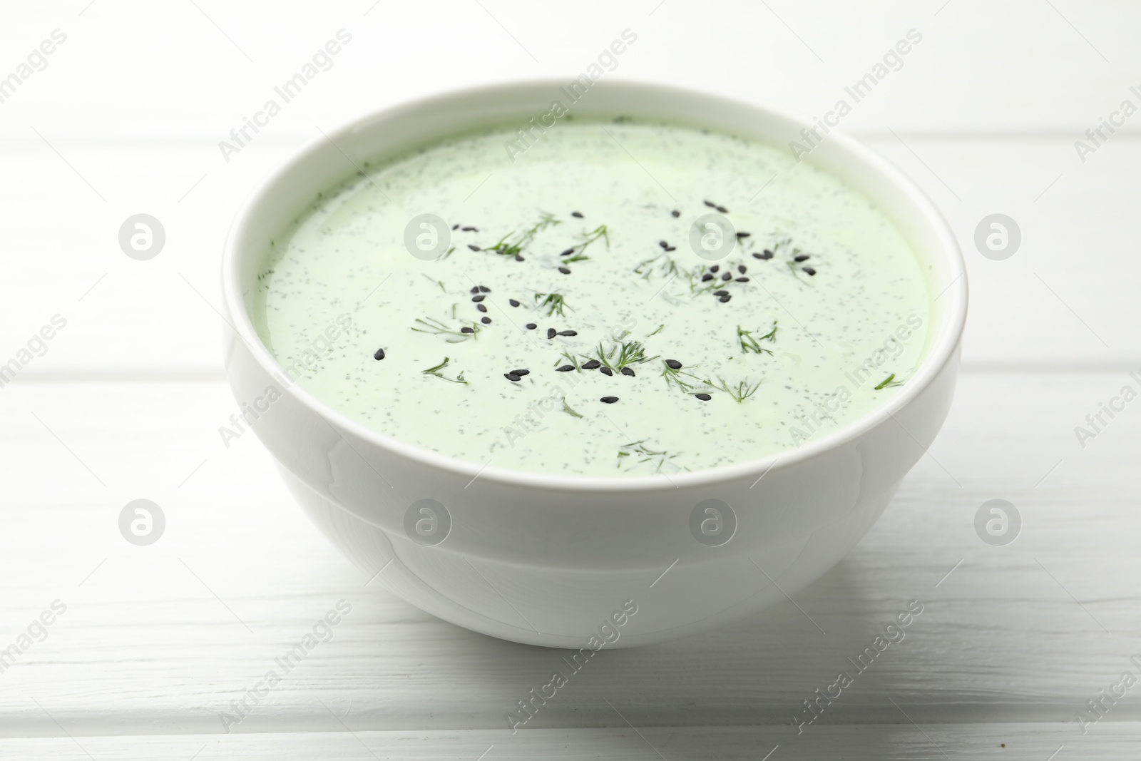 Tasty cucumber soup with dill and sesame seeds on white wooden table, closeup Photo of Tasty cucumber soup with dill and sesame seeds on white wooden table, closeup