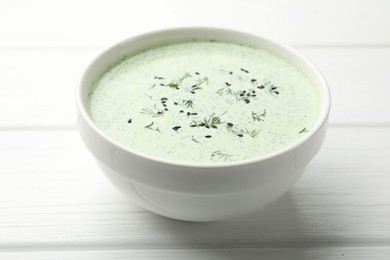 Photo of Tasty cucumber soup with dill and sesame seeds on white wooden table, closeup