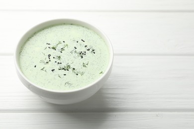 Photo of Tasty cucumber soup with dill and sesame seeds on white wooden table, closeup. Space for text
