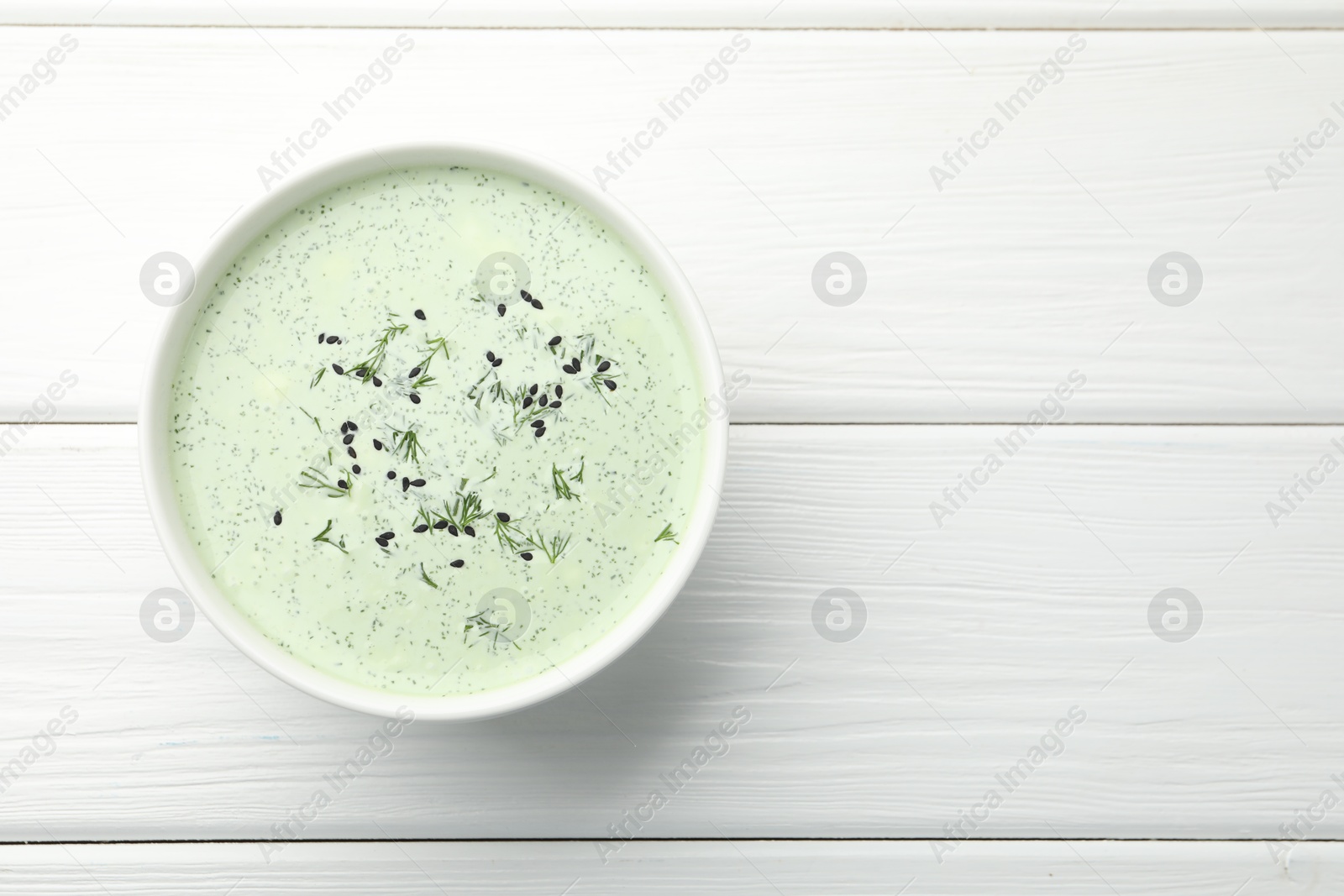 Tasty cucumber soup with dill and sesame seeds on white wooden table, top view. Space for text Photo of Tasty cucumber soup with dill and sesame seeds on white wooden table, top view. Space for text