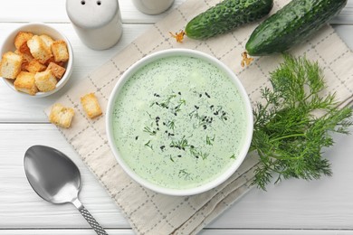 Photo of Tasty cucumber soup, croutons and ingredients on white wooden table, flat lay