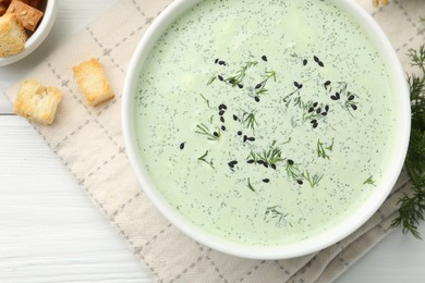 Photo of Tasty cucumber soup, croutons and ingredients on white wooden table, flat lay