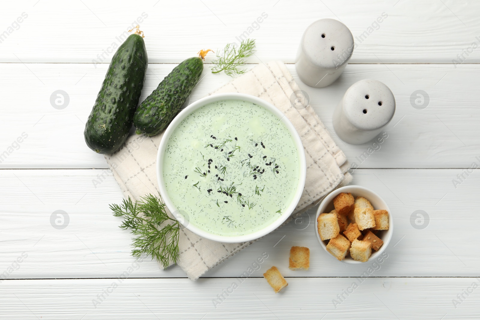 Tasty cucumber soup, croutons and ingredients on white wooden table, flat lay Photo of Tasty cucumber soup, croutons and ingredients on white wooden table, flat lay
