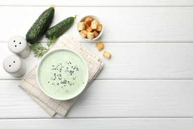 Photo of Tasty cucumber soup, croutons and ingredients on white wooden table, flat lay. Space for text