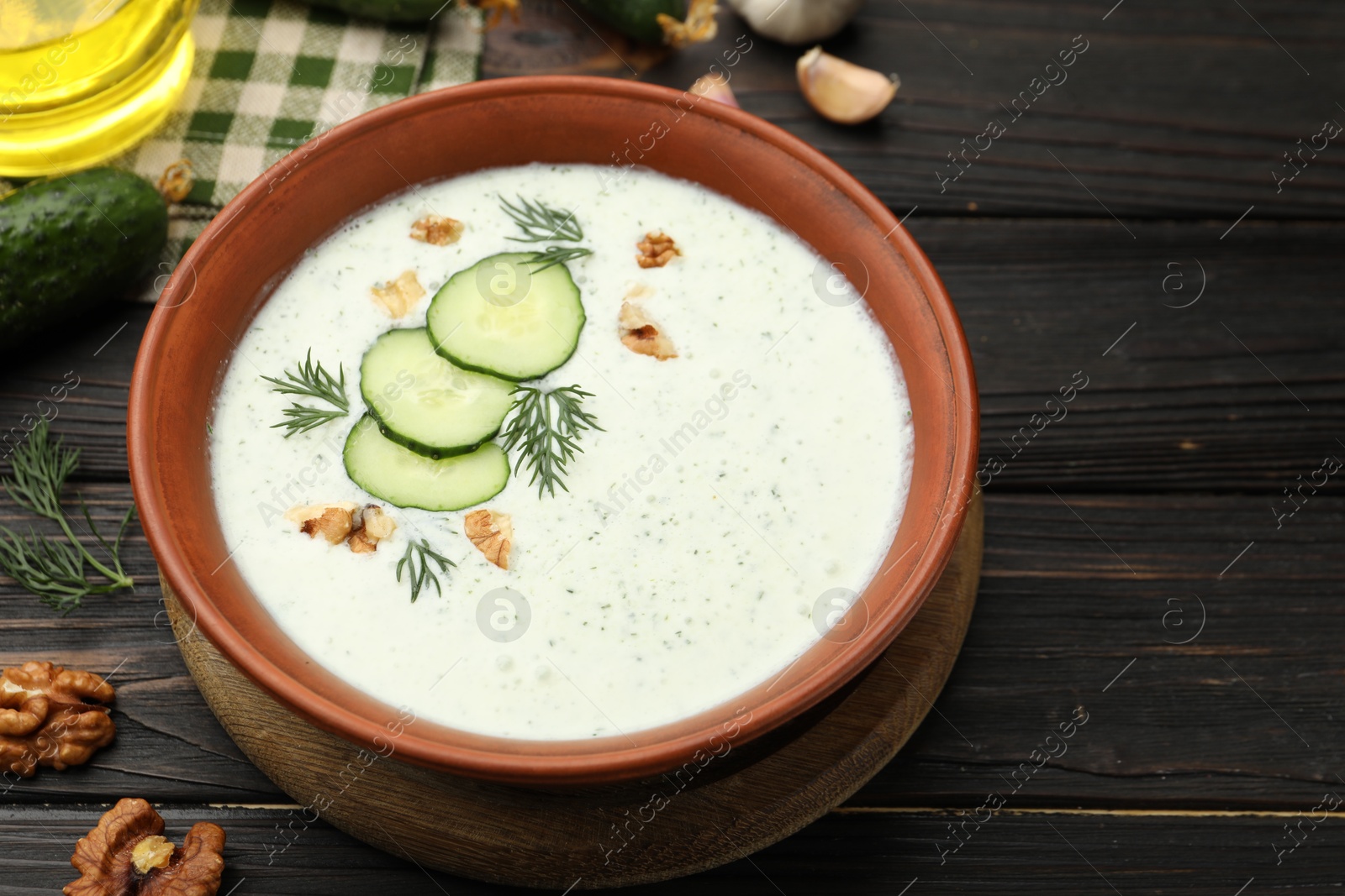 Tasty cucumber soup with dill, walnuts and ingredients on wooden table, closeup Photo of Tasty cucumber soup with dill, walnuts and ingredients on wooden table, closeup