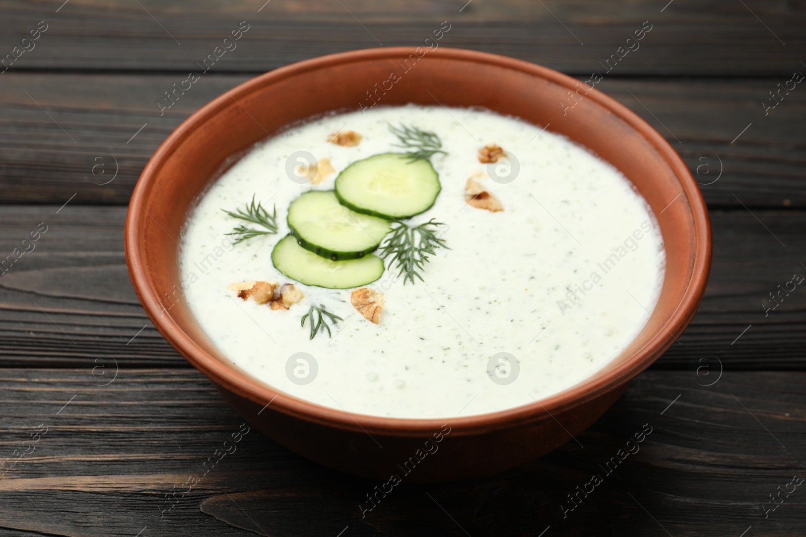 Tasty cucumber soup with dill and walnuts on wooden table, closeup Photo of Tasty cucumber soup with dill and walnuts on wooden table, closeup