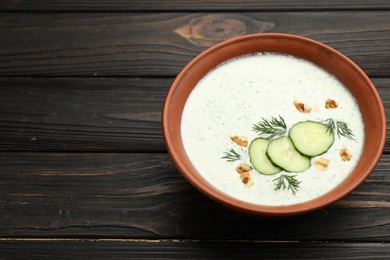 Photo of Tasty cucumber soup with dill and walnuts on wooden table, closeup. Space for text