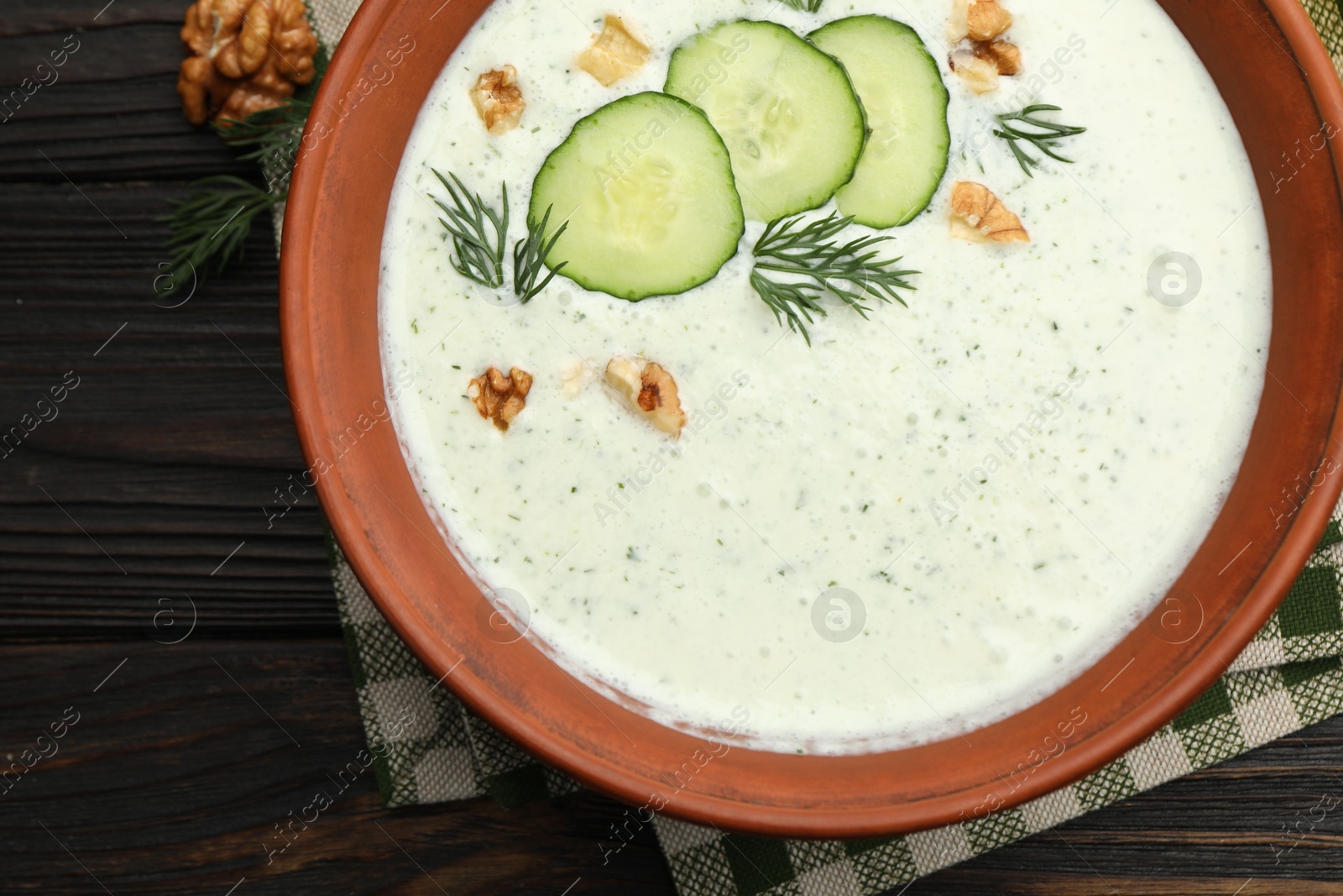 Tasty cucumber soup with dill and walnuts on wooden table, top view Photo of Tasty cucumber soup with dill and walnuts on wooden table, top view