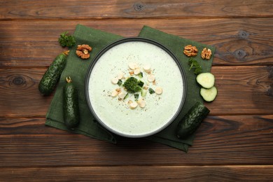Photo of Tasty cucumber soup with croutons and broccoli on wooden table, flat lay